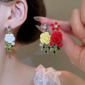 Elegant floral pearl earrings with colorful rhinestones and green leaf details on model