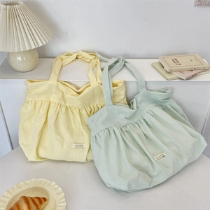 Detail of soft pleated canvas tote bags in yellow and mint green colors with knot handles