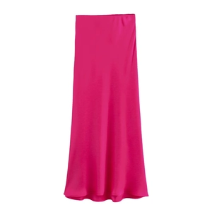 Détail de la jupe midi en satin fuchsia montrant la texture soyeuse et le drapé