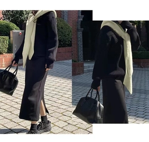 Detail of light green knitted shawl cape styled with black sweater and midi skirt