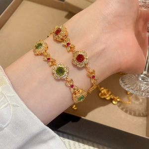 Detail of 24K gold plated beaded flower bracelets with red and green gemstone accents