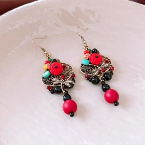 Detail of vintage earrings with dragonfly pendants, red flowers and resin bead accents