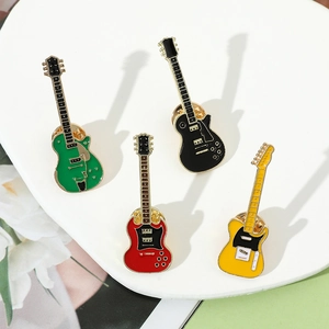 Close-up of four colorful enamel electric guitar brooches on a white ceramic tray