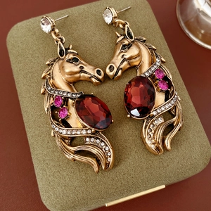 Gros plan de boucles d'oreilles cheval vintage avec strass rouges sur écrin