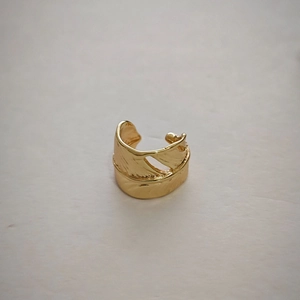 Detailed macro shot of vintage gold feather ear cuff showing intricate engraved textures