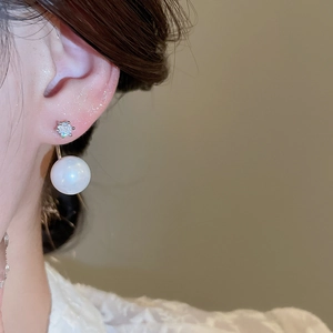 Close-up of sparkling zircon geometric hoop earrings with silver pins on female model