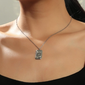 Close-up of vintage tarot card necklace with LE MONDE engraving on a silver pendant