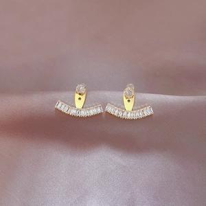 Detail of gold geometric earrings with sparkling zircon crystals on silk fabric