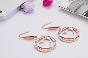 Detailed macro view of heart-shaped rose gold earrings with sparkling rhinestone pavé setting