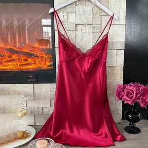 Elegant dark red satin nightgown with V-neck lace trim hanging in a warm interior setting
