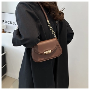 Close-up of brown shoulder bag with gold metal lock and leather chain strap detail