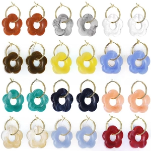 Flat lay of colorful acrylic flower earrings with gold hoops in twelve various marble textures