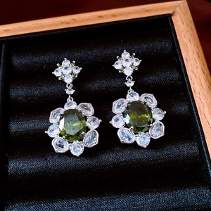 Detailed view of vintage flower earrings with green gemstone and zirconia on black velvet