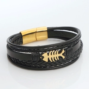 Detail of multi-layer black braided leather bracelet with golden fishbone and magnetic clasp