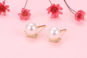 Macro detail of natural pearl earrings with rainbow zirconia in gold crescent setting