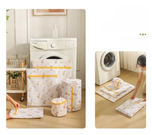 Mesh laundry bags set with bear print and yellow zippers shown next to a washing machine