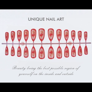 Close-up of red gradient press-on nails with 3D gold cherry patterns on pink tray