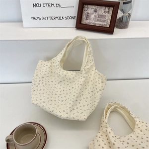 Detail of floral corduroy tote bags in cream and pink on a stylish display stand