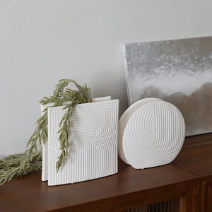 Modern white ceramic geometric vases with spiral textures on dark wood cabinet