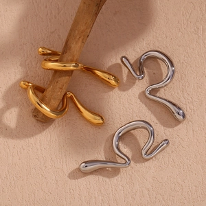 Detailed view of liquid metal wave ear cuffs in polished gold and silver finishes