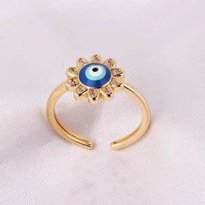 Minimalist gold evil eye ring with blue enamel and crystal petals on pink fabric