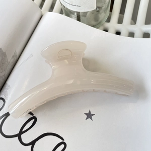 Macro shot of large cream hair claw clip on magazine with elegant lighting detail