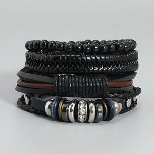 Detailed view of 4-piece layered black leather bracelet set with woven and metal accents
