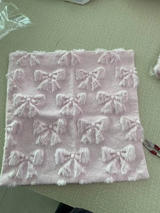 Detailed macro view of pink plush pillowcase featuring a raised 3D bow texture