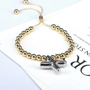 Detail of adjustable beaded bracelet with golden beads and silver letter X charm