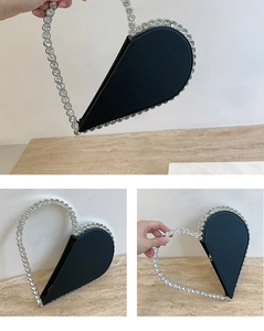 Detail of heart-shaped clutch bag featuring sparkling rhinestone edges and ring handle