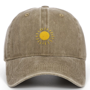 Detail of yellow sun embroidery on vintage washed khaki cotton baseball cap