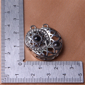 Macro shot of sun and moon magnetic pendant next to a scale ruler on brown silk