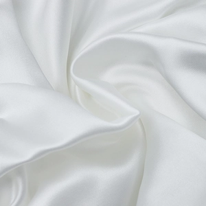 Detailed macro shot of premium white silk fabric showing soft drape and satin luster