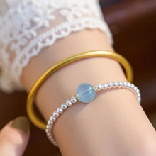 Detail of natural freshwater pearl beaded bracelet paired with a matte gold bangle