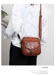 Sac bandoulière vintage en cuir marron avec rivets métalliques porté par un mannequin