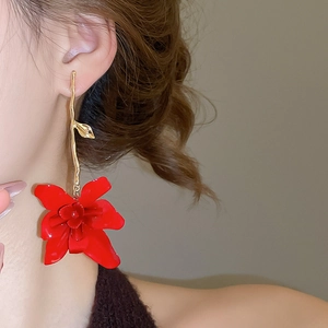 Close-up of elegant red flower pendant earrings with gold branch details on model