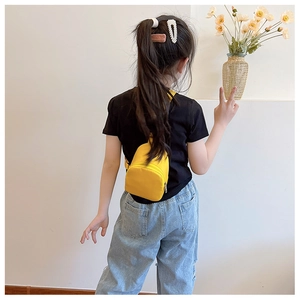 Detail showing a bright yellow mini chest bag worn as a crossbody by a child