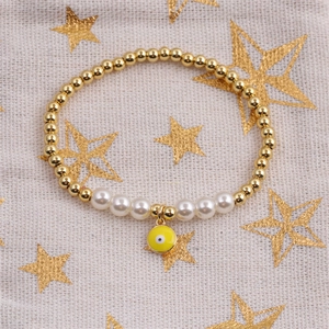 Détail d'un bracelet de perles dorées et blanches avec pendentif œil maléfique jaune