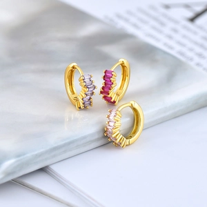 Macro shot of gold S925 huggie hoop earrings with baguette-cut colored zircons