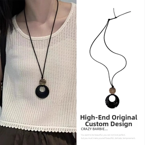 Macro detail view of the ethnic black resin circle pendant on a stylish long cord necklace