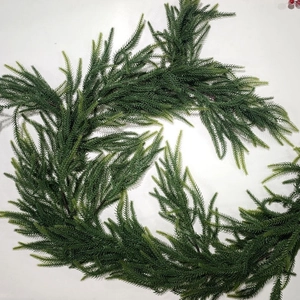 Macro shot of realistic green artificial Norfolk pine garland on a white background