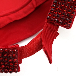 Detail of red rhinestone sun visor featuring adjustable velcro strap and cotton fabric