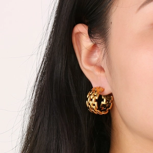 Close-up of vintage gold-plated C-shaped earrings with a textured chain design on ear