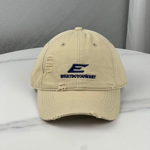 Distressed beige cotton baseball cap with blue embroidery on marble surface