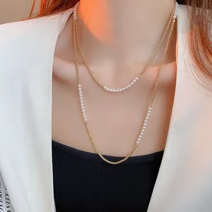 Détail d'un collier double rang en or et perles blanches sur une tenue élégante