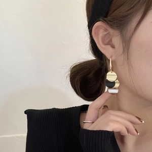 Close-up of vintage S925 silver needle tassel earrings with gold and black discs