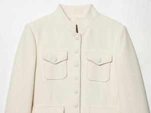 Detail of off-white tweed jacket featuring a stand collar and woven fabric texture