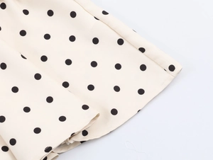 Gros plan sur le tissu beige à pois noirs avec détails de l'ourlet plissé