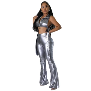 Dettaglio del crop top metallizzato argento con zip e pantaloni a zampa con lacci