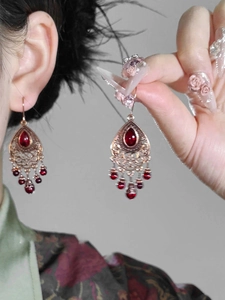 Detailed close-up of bohemian waterdrop earring with red stones and beaded tassels